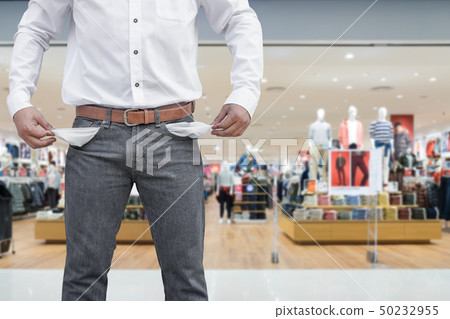 Man showing his empty pockets on blur mall Man showing his empty pockets on blur mall 50232955