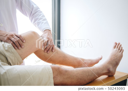 Doctor physiotherapist assisting a male patient 50243093