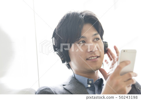 A young man listening to music on a smartphone A young man listening to music on a smartphone 50243198