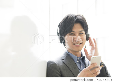 A young man listening to music on a smartphone A young man listening to music on a smartphone 50243203