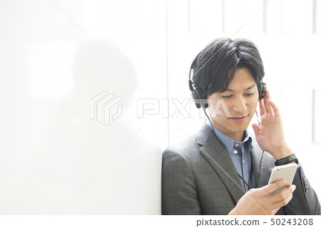 A young man listening to music on a smartphone A young man listening to music on a smartphone 50243208