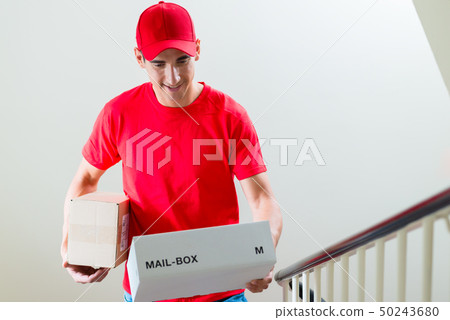 Male courier in uniform looking at mail boxes 50243680