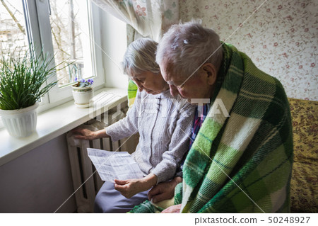 Woman holding cash in front of heating radiator. 50248927