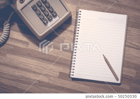 Pencil on blank notebook with vintage dial phone Pencil on blank notebook with vintage dial phone 50250330