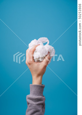 Hand holding plastic bag against blue background. 50251608