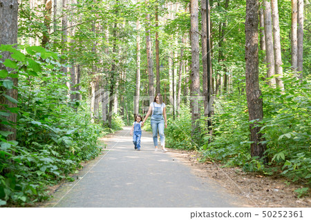 Family, leisure and nature concept - Portrait of mother with her little daughter walking in the 50252361