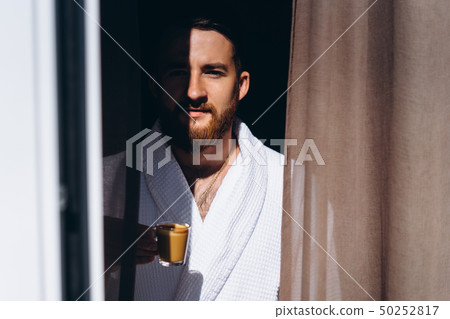 Male in white bathrobe with coffee mug in hand. Male in white bathrobe with coffee mug in hand. 50252817