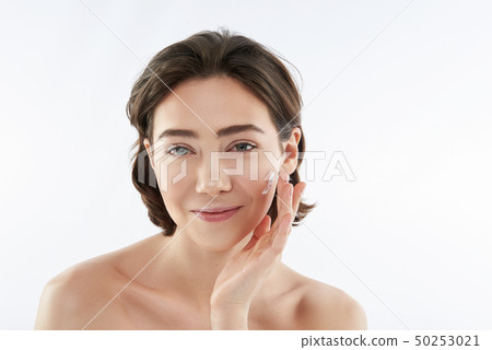 Pretty smiling woman applying cream on face Pretty smiling woman applying cream on face 50253021