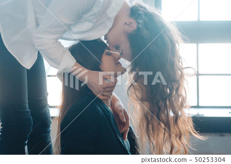 Close up young woman thoughtfully kissing woman at home 50253304