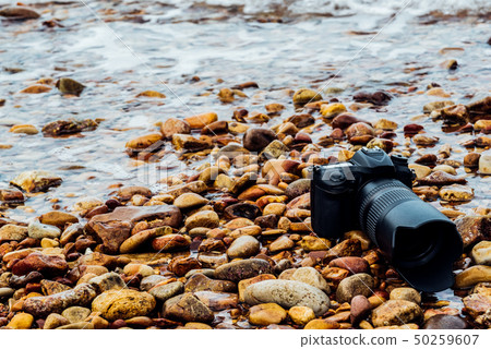 DSLR camera on stone beach wet from water sea wave 50259607