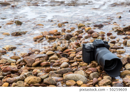 DSLR camera on stone beach wet from water sea wave DSLR camera on stone beach wet from water sea wave 50259609