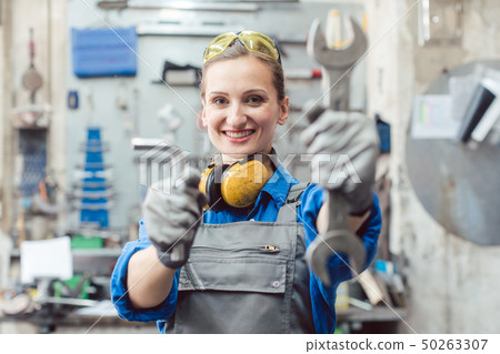 Woman mechanic showing tools to the camera 50263307