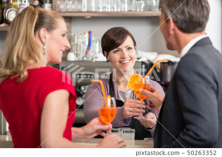 Waitress giving cocktail glass to man 50263352