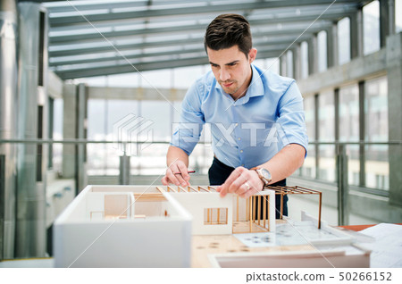 Young businessman or architect with model of a house standing in office, working. 50266152