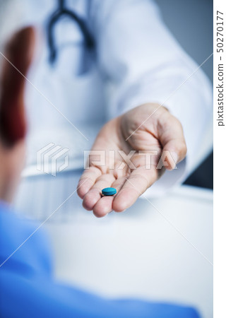 doctor man giving a blue pill to a senior man doctor man giving a blue pill to a senior man 50270177