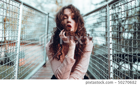 Fashion portrait of trendy young woman sitting near the netting rabitz 50270682