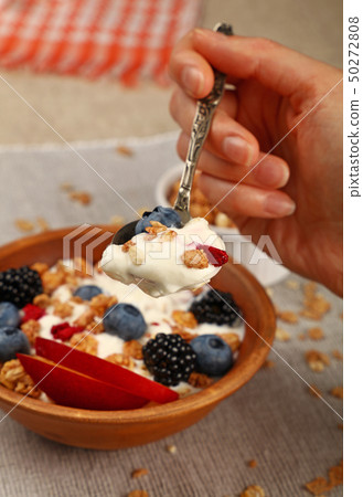 Woman eating muesli granola breakfast with yogurt Woman eating muesli granola breakfast with yogurt 50272808