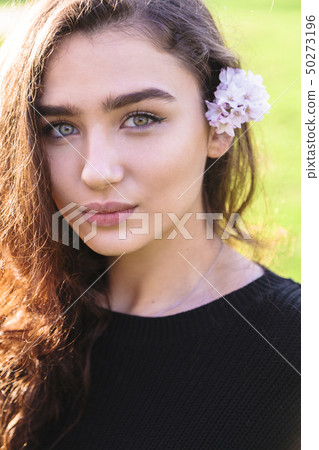 Portrait of woman with pink flower behind her ear 50273196