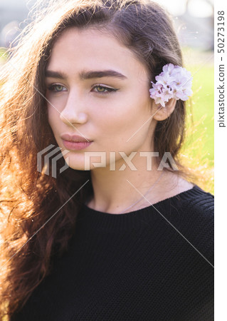 Portrait of woman with pink flower behind her ear 50273198