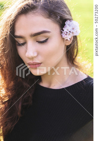 Young woman with pink flower tucked behind her ear 50273200
