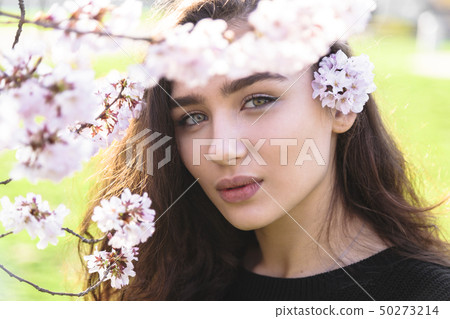 Girls face in frame of blossom tree branch outdoor Girls face in frame of blossom tree branch outdoor 50273214