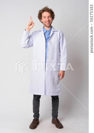 Full body shot of happy man doctor with curly hair pointing up Full body shot of happy man doctor with curly hair pointing up 50275383
