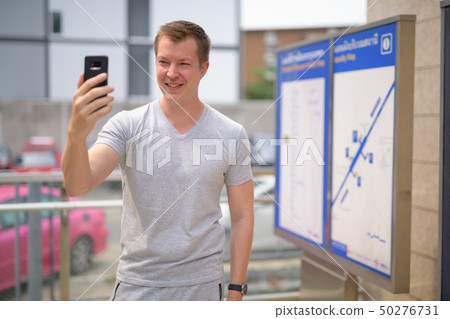 Young happy tourist man taking selfie against view of map at the train station in Bangkok 50276731
