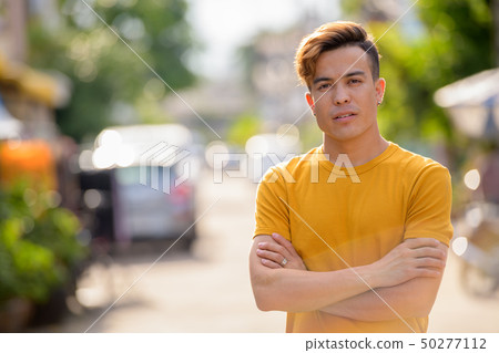 Young Asian man with arms crossed in the streets outdoors Young Asian man with arms crossed in the streets outdoors 50277112