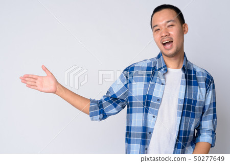 Portrait of happy young Asian hipster man showing something Portrait of happy young Asian hipster man showing something 50277649