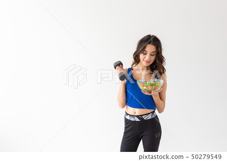 Healthy lifestyle, people and sport concept - Healthy young woman with vegetables and dumbbells 50279549