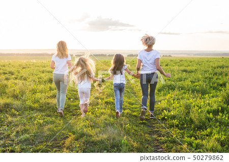 Family, summer and holiday concept - Group of women and girls going away in green field 50279862