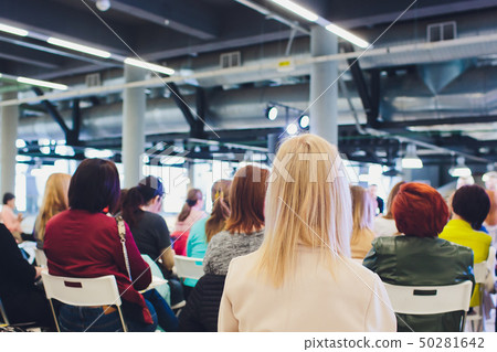 People sit in armchairs in conference room, focus on blonde woman nape. 50281642
