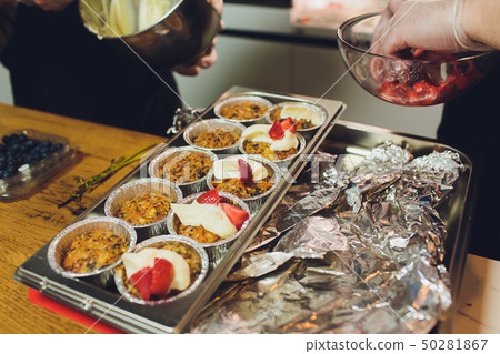 A chef decorates many plates of cake. 50281867