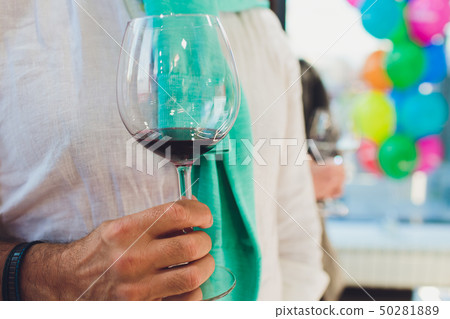 man hand holding glass of wine in the room. party, drinks, holidays, luxury and celebration concept. man hand holding glass of wine in the room. party, drinks, holidays, luxury and celebration concept. 50281889