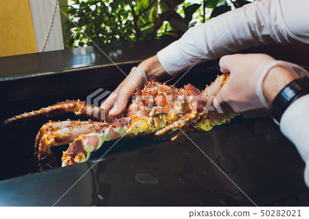Chef cook restaurant in white uniform is holding fresh big kamchatka crab. Concept healthy food 50282021