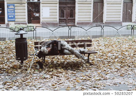 Homeless sleeping on the benches in the autumn park Homeless sleeping on the benches in the autumn park 50283207