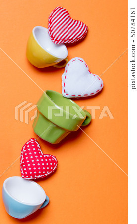 Heart shapes and color cups on orange background. 50284161
