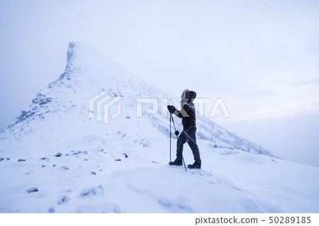 Man climber with trekking poles standing on snowy Man climber with trekking poles standing on snowy 50289185