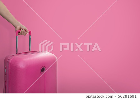 Hand holding traveler pink suitcase or cabin size  50291691
