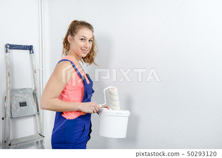 pretty young woman painting the wall 50293120