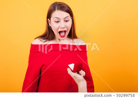 Portrait of beautiful woman shocked while being proposed over yellow background Portrait of beautiful woman shocked while being proposed over yellow background 50299758
