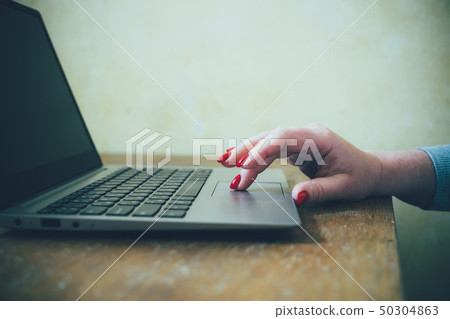 Womans hand with red nails on laptop keyboard, lady using laptop on old vintage table Womans hand with red nails on laptop keyboard, lady using laptop on old vintage table 50304863