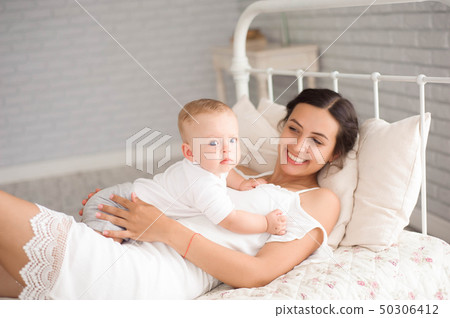 A Mother and baby child on a white bed. 50306412