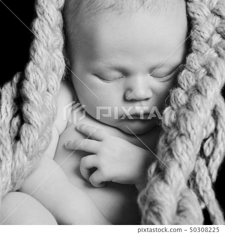 naked newborn baby sleeps curled up in a ball in a 50308225