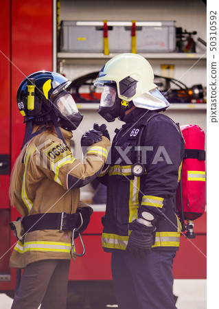 Picture of firefighters women and men in helmet and mask looking at each other and doing handshake Picture of firefighters women and men in helmet and mask looking at each other and doing handshake 50310592