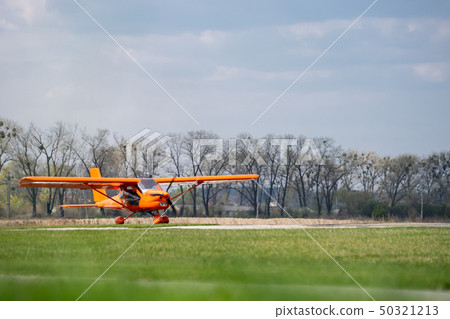 small red charter airplane waiting on a green field to take off 50321213