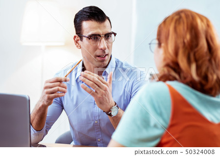 Smart dark haired man gesticulating with his hands Smart dark haired man gesticulating with his hands 50324008
