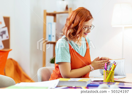 Positive red haired young woman opening a book Positive red haired young woman opening a book 50324197