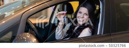Happy woman buyer examines her new vehicle in car dealership Happy woman buyer examines her new vehicle in car dealership 50325766