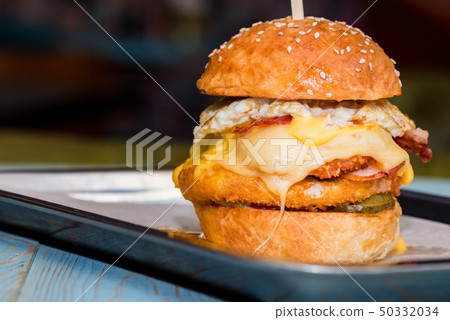 Close up tall tasty burger with cheese and egg served on tray 50332034